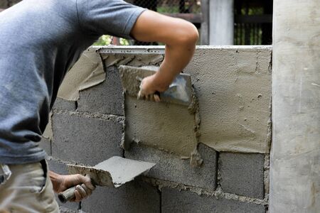 Asian plasterer plastering concrete walls