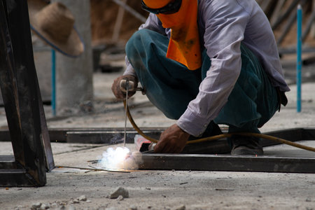 The laborer is welding steel in the construction.