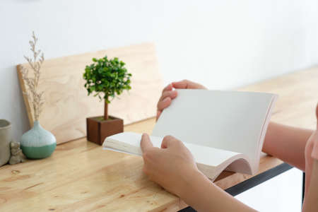 Mockup image of a woman reading a book on table with blank pages of bookの写真素材