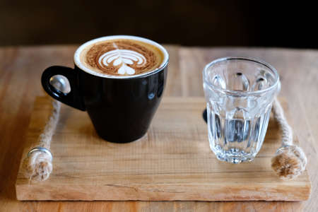 cappuccino coffee cups and warm water were served together on a wooden tray.の写真素材