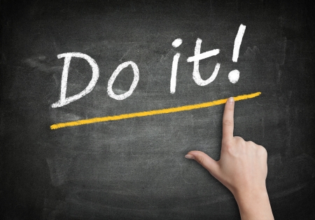 Motivation text "Do it!" with a hand pointing to it on a blackboardの写真素材