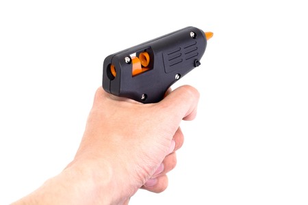 Glue pistol in a hand isolated on white background.の写真素材
