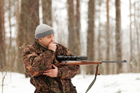 Smoking huter with rifle at winter forest.の写真素材