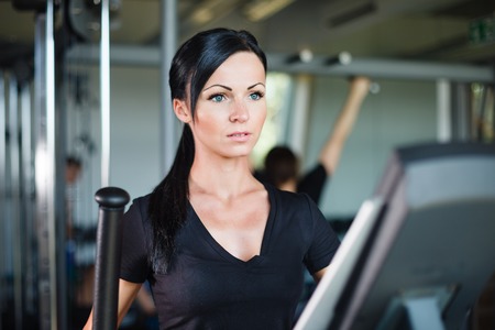 Running brunette in black t-shirt at gym.