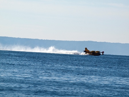 Yellow fire fighter airplan landing at blue seaのeditorial素材