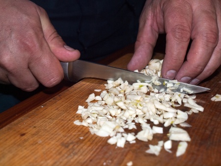 Dicing garlic on a chopping board.