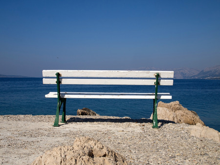 Idyllic view at bench near the blue seaの写真素材