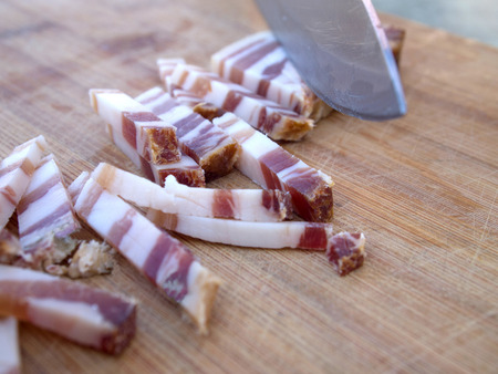 Cutting smoked bacon close up on wooden boardの写真素材