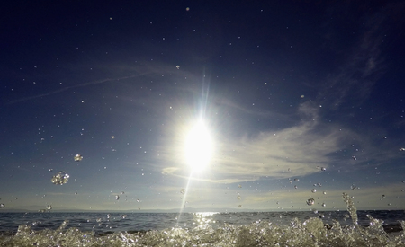 Landscape scene of water splash on beach with sun in backgroundの写真素材