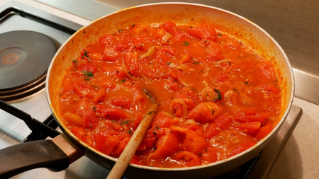 Cooking organic tomato sauce with mediterranean herbs in panの写真素材