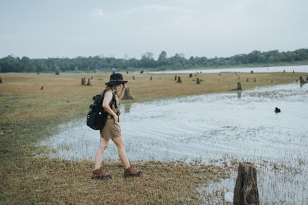 Young woman traveler with backpack and hat standing on the grassland.の写真素材