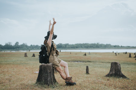 Back view of Asian woman with backpack standing on stump in the field.の写真素材
