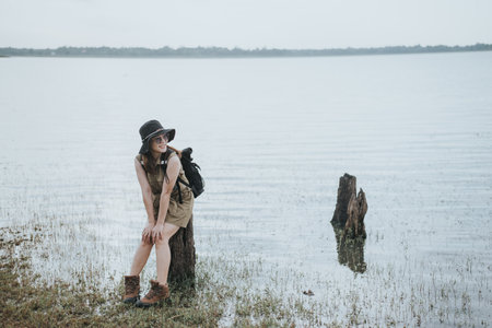 stylish hipster girl in hat and shorts posing on the shore of the lakeの写真素材