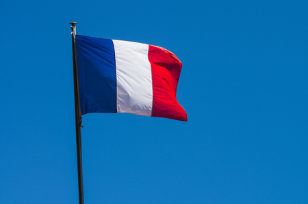 French flag against blue cloudy sky on streetの写真素材