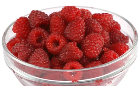 Close up of ripe raspberries in a glass bowl isolated on whiteの写真素材