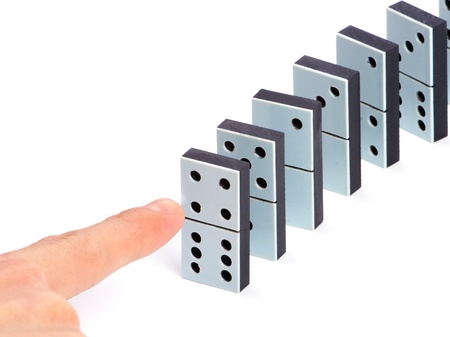 Hand ready to push domino pieces to cause chain reactionの写真素材