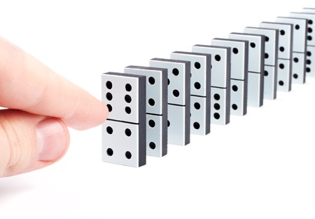 Hand ready to push domino pieces to cause chain reactionの写真素材