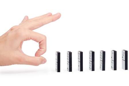 Hand ready to push domino pieces to cause chain reactionの写真素材
