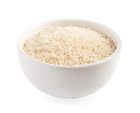 Uncooked rice in a ceramic bowl isolated on whiteの写真素材