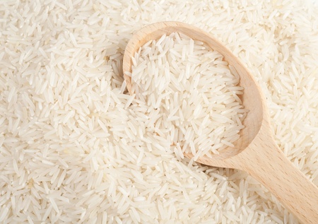 Uncooked basmati rice in a wooden spoonの写真素材