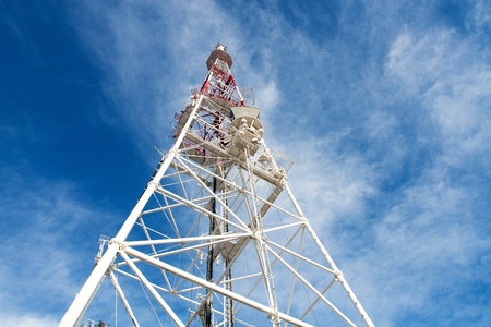 Telecommunication tower with antennas against blue sky background