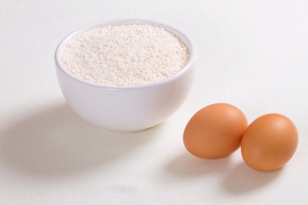 Eggs and wheat flour in a plate on white backgroundの写真素材
