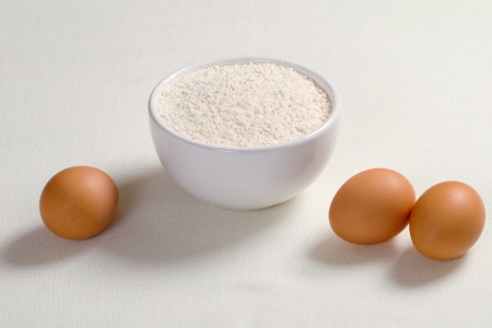 Eggs and wheat flour in a plate on white backgroundの写真素材