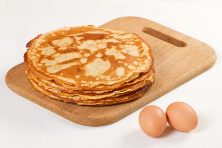 Pile of pancakes with some flour and eggs on white backgroundの写真素材