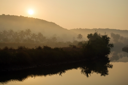 Tropical sunrise over misty riverの写真素材