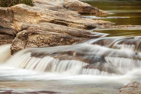 Water stream running over the rocks in the foresの写真素材