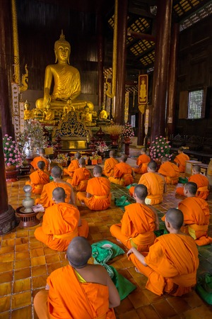 CHIANG MAI, THAILAND - NOVEMBER 22, 2013: Young buddhist monks praying in front of the Buddha image in the temple in Chiang Mai, Thailand on 22 November, 2013のeditorial素材