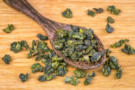Green tea in a wooden spoon on a wooden boardの写真素材