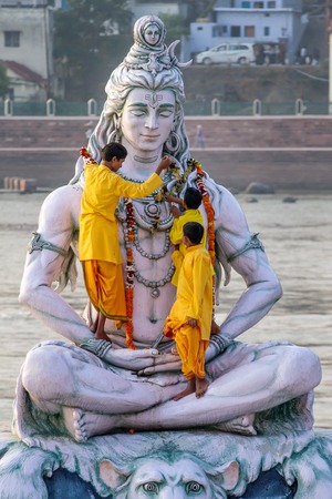 RISHIKESH, INDIA - NOVEMBER 13, 2012: Servants decorate large statue of Hindu Lord Shiva with flowers for the Ganga Aarti ceremony on November 13, 2012 in Rishikesh, India.のeditorial素材
