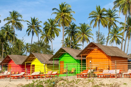 Colorful huts on the sandy beach with palm trees background in Goa, Indiaの写真素材