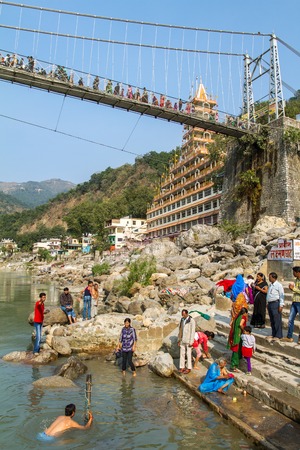 RISHIKESH, INDIA - NOVEMBER 11, 2012: People performing a ritual bath in the holy river of Ganges believing in purification on all levels of existence.のeditorial素材