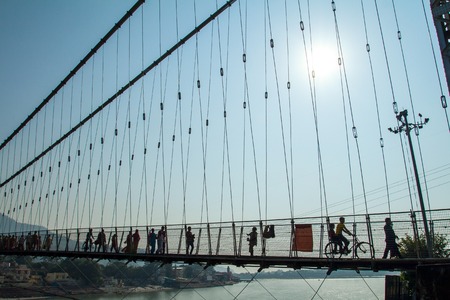 RISHIKESH, INDIA - 2012 NOVEMBER 13: People crossing Lakshman Jhula bridge over Ganges on November 13, 2012 in Rishikesh, India.のeditorial素材
