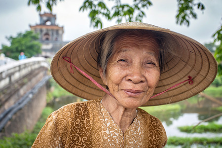 HUE, VIETNAM - APRIL 3, 2014: Unidentified Vietnamese woman wearing traditional conical hat poses for the camera in Hue, Vietnam on April 3, 2014.のeditorial素材