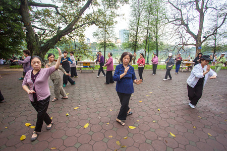 HANOI, VIETNAM - APRIL 6, 2014: Group of Vietnamese seniors practice Tai Chi early in the morning on the bank of Hoan Kiem lake on April 6, 2014 in Hanoi.のeditorial素材