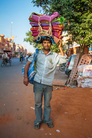 JAIPUR, INDIA - NOVEMBER 25, 2012: Unidentified Indian man carries colorful blankets on his head on November 25, 2012 in Jaipur, Rajasthan, India.のeditorial素材