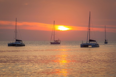 Yachts in the ocean at sunsetの写真素材