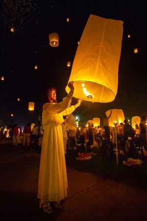 CHIANG MAI, THAILAND - NOVEMBER 8, 2014: Unidentified woman releases Khom Loi, the sky lanterns during Yi Peng or Loi Krathong festival on November 8, 2014 in Mae Jo University, Chiang Mai, Thailand.のeditorial素材