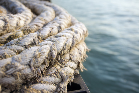 Old naval rope on a pier against blue waterの写真素材