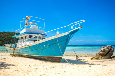 Old fishing boat stranded on a beach in sunny dayの写真素材