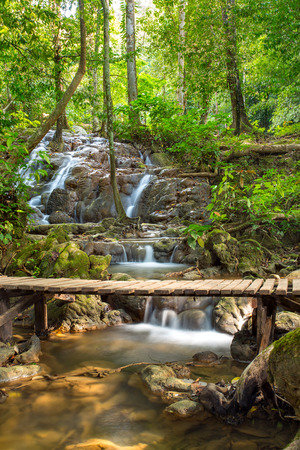 Tropical rain forest landscape with wooden bridge over the beautiful stream with cascades in Thailandの写真素材