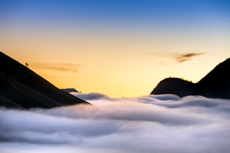 Mountain silhouettes and fog in the valley on the sunrise in Bromo Tengger Semeru National Park in Java, Indonesiaの写真素材