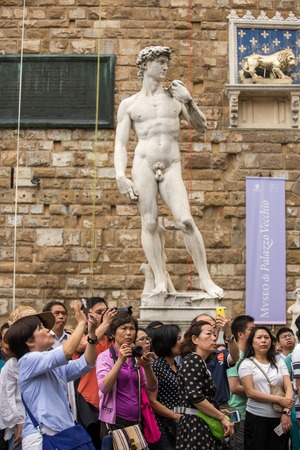 FLORENCE, ITALY - SEPTEMBER 16: Group of tourists making photos on Palazzo Vecchio with a David statue on background in Florence on September 16, 2015. Palazzo Vecchio is a World Heritage Site in Tuscanyのeditorial素材