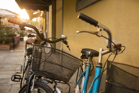 Italian bicycles with baskets parked on empty sunny streetの写真素材