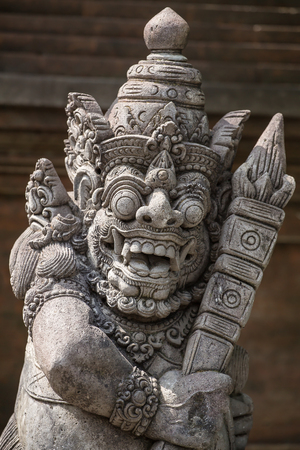 Traditional guard demon statue carved in dark stone on Bali island, Indonesiaの写真素材