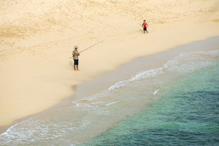 Java, Indonesia - April 11, 2015: Unknown fisherman with a boy with fishing rod on the beach on southern coast of Java, Indonesiaのeditorial素材