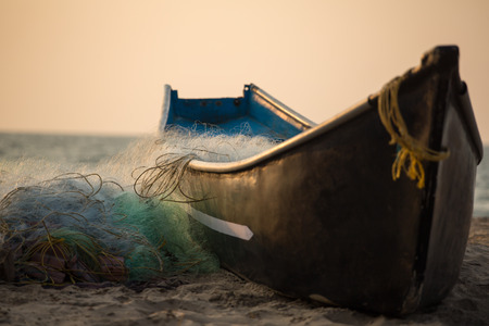 Fisherman boat with fishing nets on the Gokarna beach near the ocean in Karnataka, Indiaの写真素材